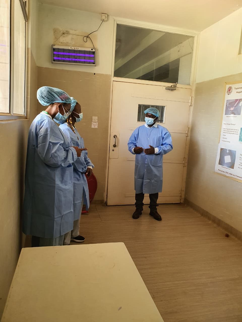 Staff in surgical gowns and caps at the entrance to a controlled room